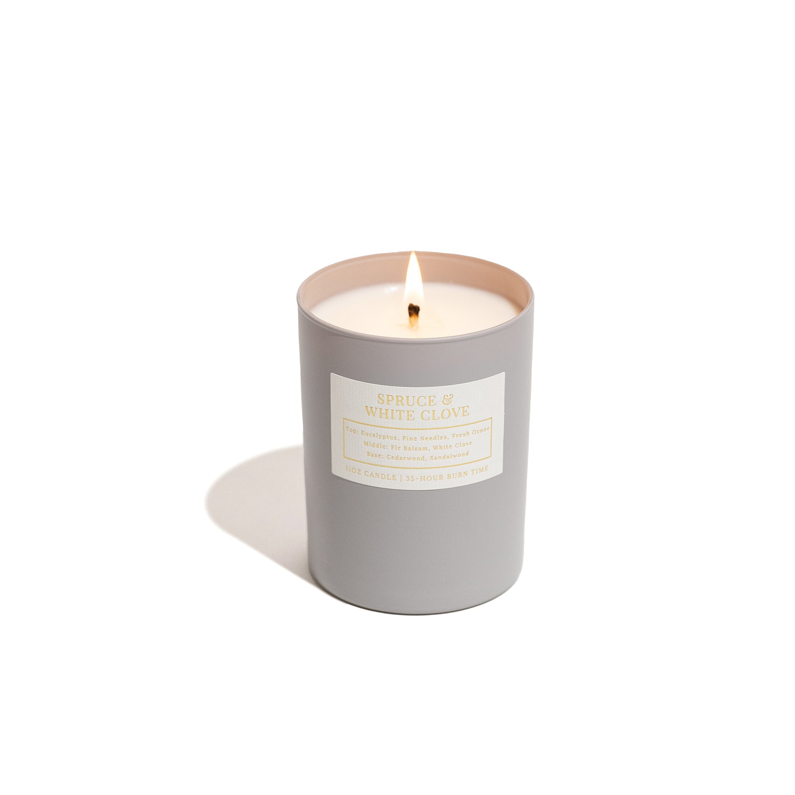 Spruce and white clove candle on white background in grey vessel. 